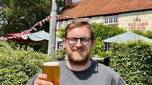 Freddie holding a pint outside a pub