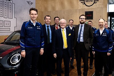 Freddie with fellow Lib Dem MPs standing in front of a car at the BMW Mini Plant