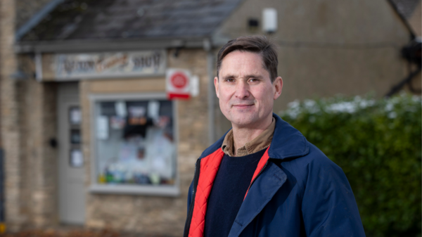 Charlie stands in front of a village post office